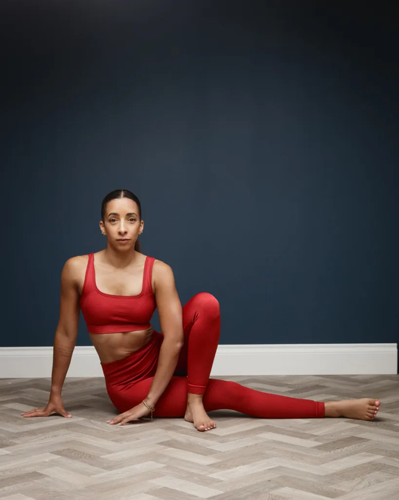 Woman in red activewear stretching on wooden floor.