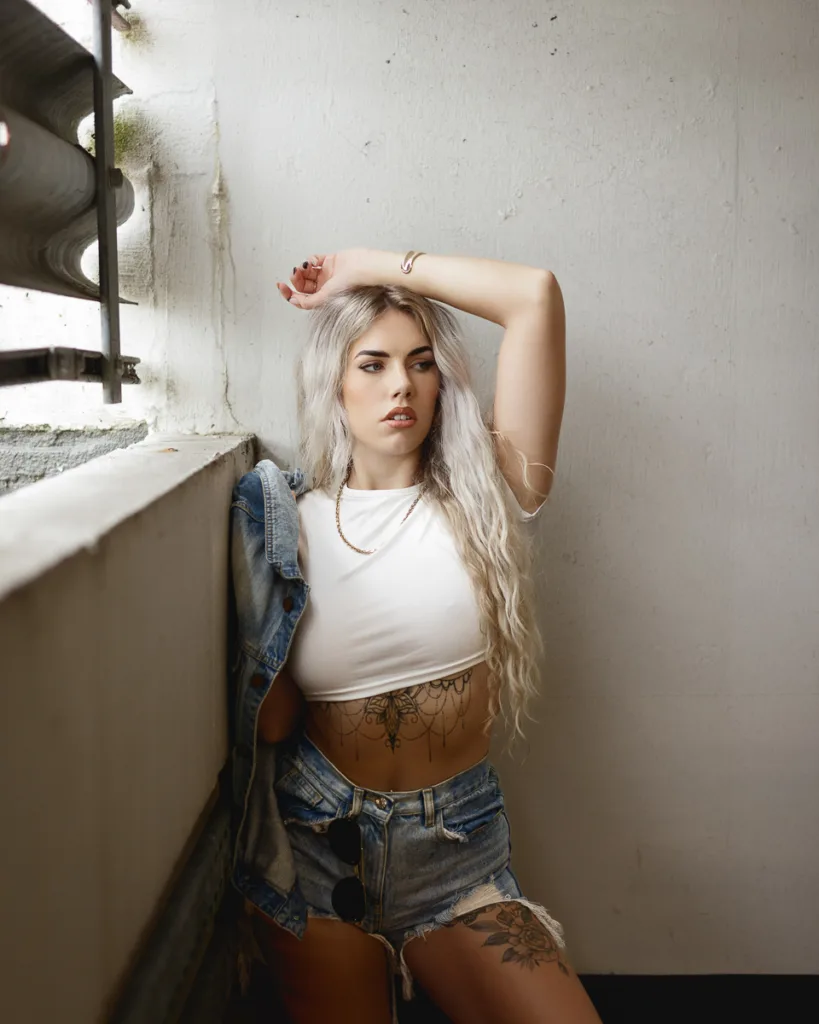 Woman posing in denim shorts, white crop top.